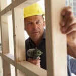 Contractor Carpenter in yellow helmet holding tool and wood performance bond